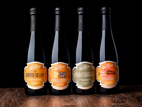 4 Bruery bottles lined up side by side on a dark wooden table